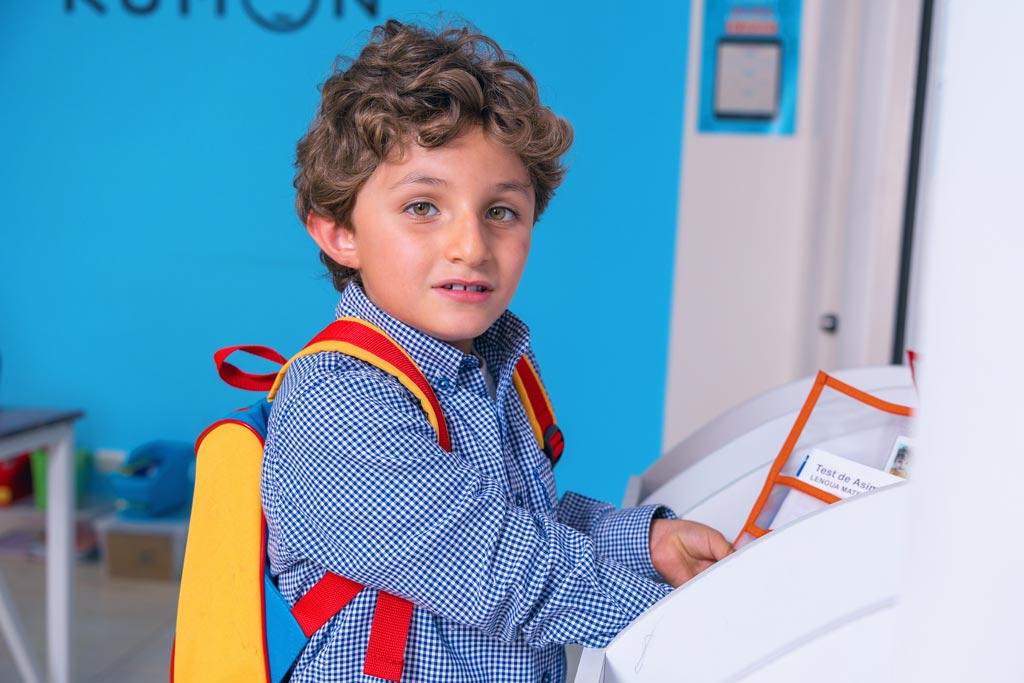 Niño entregando sus tareas en un centro Kumon, listo para continuar su aprendizaje con el método individualizado-Uruguay