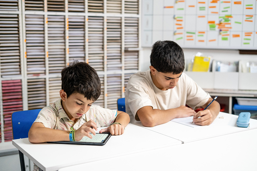 Dos estudiantes en un aula de Kumon, uno trabajando en una tableta y otro escribiendo en papel-Uruguay