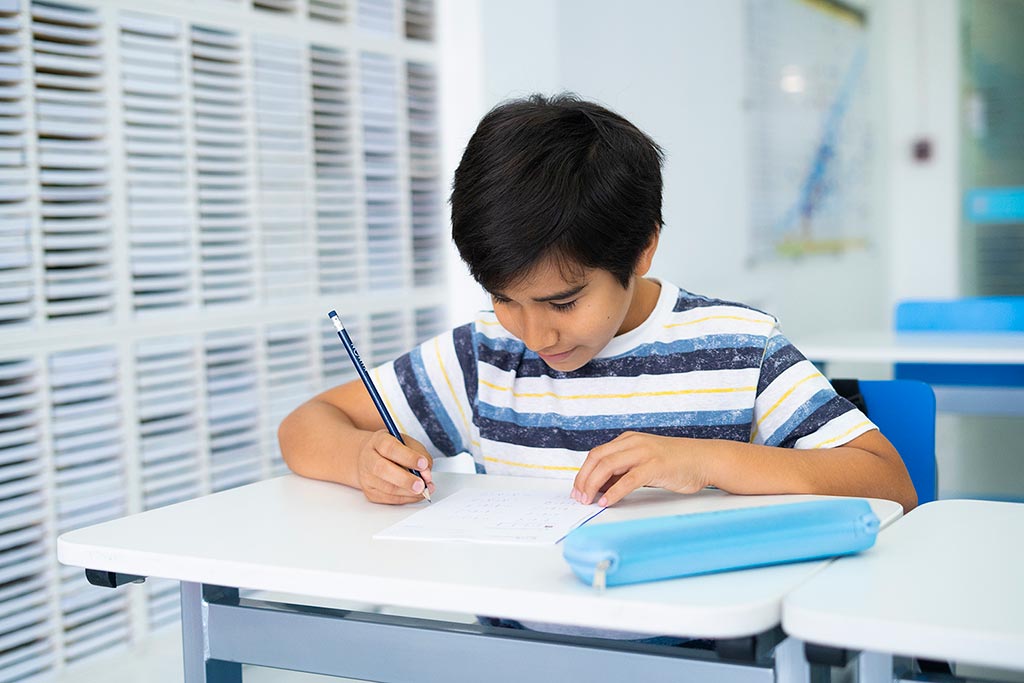 Niño concentrado resolviendo ejercicios en papel como parte del método de estudio individualizado de Kumon-Uruguay