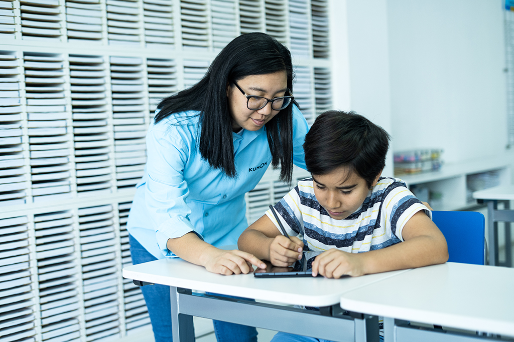 Orientador guiando a un estudiante mientras utiliza una tableta para el aprendizaje individualizado en el aula-Uruguay
